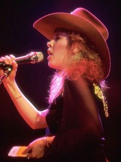 a woman in a cowboy hat singing into a microphone