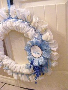 a baby shower wreath with blue and white ribbons on it's front door frame