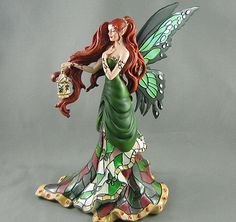 a fairy figurine holding a purse and wearing a green dress with butterfly wings