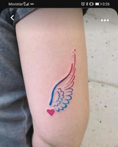 a small tattoo on the arm of a woman with blue and red wings painted on it