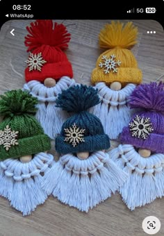 several knitted hats with snowflakes and tassels sitting on a table