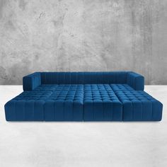 a blue couch sitting on top of a white floor next to a concrete wall and cement walls