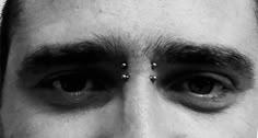 a man with piercings on his forehead looking at the camera