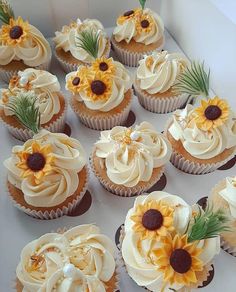 cupcakes with frosting and sunflowers on them are arranged in a box