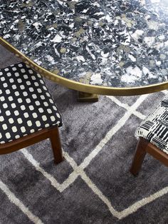 a black and white patterned chair next to a round table with two chairs on it