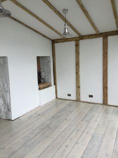 an empty room with white walls and wood floors