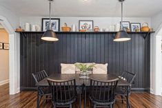 the dining room table is surrounded by black chairs and wooden shelves with pictures on them