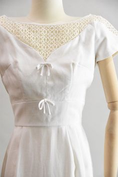 "Vintage 1950 cocktail wiggle dress. White linen with v shaped illusion neckline with scroll embroidery on top both in front and back and partially on sleeves. Two decorative bows under bust for detail. Darted bust, capped sleeves, and fitted waist. Straight skirt with kick pleat in back. Rear metal zip closure. State of garment | very good, light overall wear. Measurements ✂--- best fit | Extra Small bust | up to 35\" shoulders | not specified shoulder to waist | 15.5\" sleeves | about 4.5\" wa Fitted Dress With Bow Tie Back And Sweetheart Neckline, Fitted Dress With Bow And Sweetheart Neckline, Classic Fitted Dress With Bow, Cocktail Dress With Bow Tie Back And Fitted Design, Fitted Cocktail Dress With Bow Tie Back, Cocktail Dress With Bow Tie Back, Formal Fitted Dress With Bow Tie Back, Formal Short Sleeve Dress With Tie Back, Fitted Wedding Dress With Bow Detail