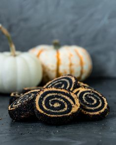 some cookies with swirl designs on them next to pumpkins