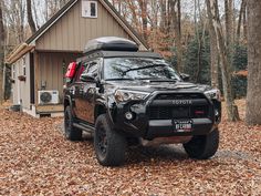 a black toyota truck parked in front of a house with trees and leaves on the ground