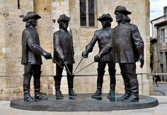 three statues of men holding hands in front of a building