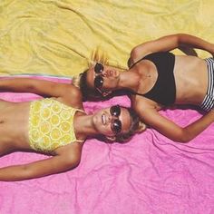 two beautiful women laying on top of a pink blanket