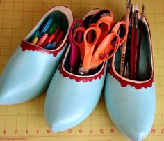 three pairs of blue shoes with pencils and markers in them