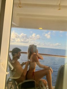 a man and woman sitting on top of a boat next to each other near the ocean