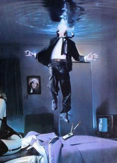 a man is suspended in the air above a bed