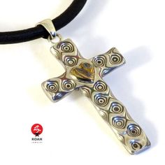 a silver cross on a black cord with a gold heart in the center and swirls around it