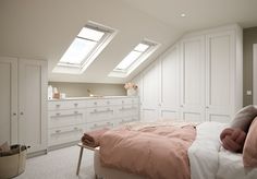 a bedroom with two skylights above the bed and dressers in front of it