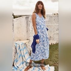 a woman in a blue and white dress stands on a towel next to a wall