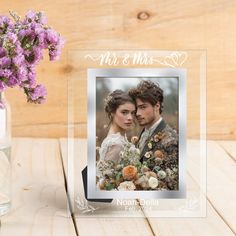 a glass photo frame with the words mr and mrs on it next to a vase filled with flowers