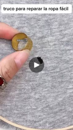 someone is holding their finger in front of a button on a t - shirt that has been stitched together