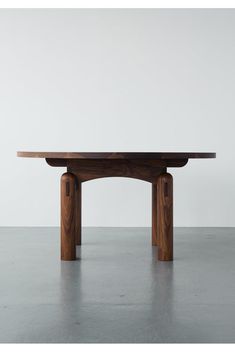 a wooden table sitting on top of a cement floor next to a white wall in an empty room