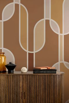 a table with vases and books on it in front of a wallpapered background