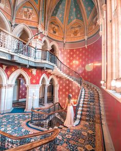 a woman in a white dress is standing at the top of a spiral stair case