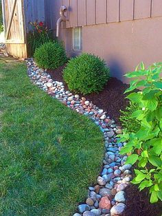 a garden with rocks and grass next to a house