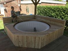 a young boy sitting on top of a wooden bench next to an inflatable hot tub