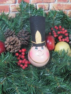 an ornament in the shape of a nutcracker surrounded by pine cones and berries