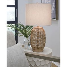 a table lamp sitting on top of a white table next to a potted plant