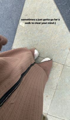 a person with their foot on the ground wearing a brown skirt and white shoes, looking down