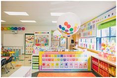 a brightly colored classroom with lots of tables and colorful balloons hanging from the ceiling above