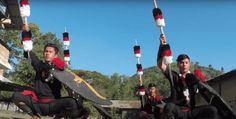 three men in black and red outfits holding up their skateboards while sitting on the ground