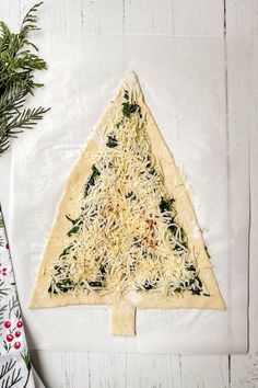 a christmas tree shaped pizza sitting on top of a white table next to a napkin