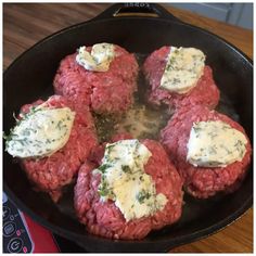 several hamburger patties are being cooked in a skillet on the stove top with cheese and herbs