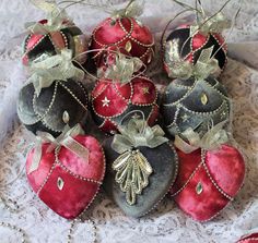 a pile of red and black ornaments sitting on top of a lace covered table cloth