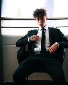 a man sitting in a chair wearing a suit and tie