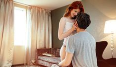 a man sitting on top of a bed next to a woman who is hugging her