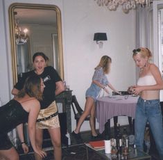 a group of people standing around a table in a living room next to a mirror