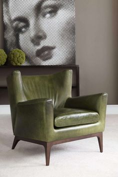 a green chair sitting in front of a painting