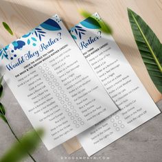 two blue and white checklists on top of a wooden table next to green leaves