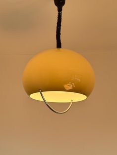 a yellow light hanging from the ceiling in a room with beige walls and flooring