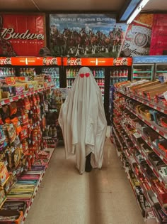 a person in a ghost costume walking through a grocery store aisle