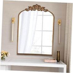 a white table with a mirror and vase on it