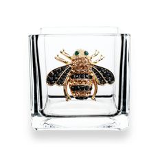 a glass with a gold and black insect in it's center, on a white background