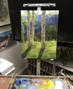 an easel with a painting on it in front of some trees