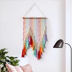 a wall hanging made out of multicolored tassels on a white wall