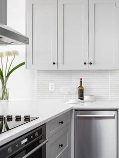 a white kitchen with stainless steel appliances and marble counter tops is seen in this image