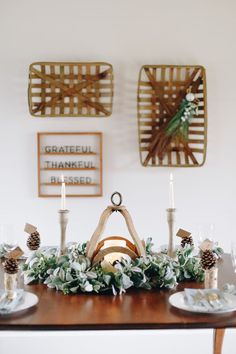 a wooden table topped with candles and greenery